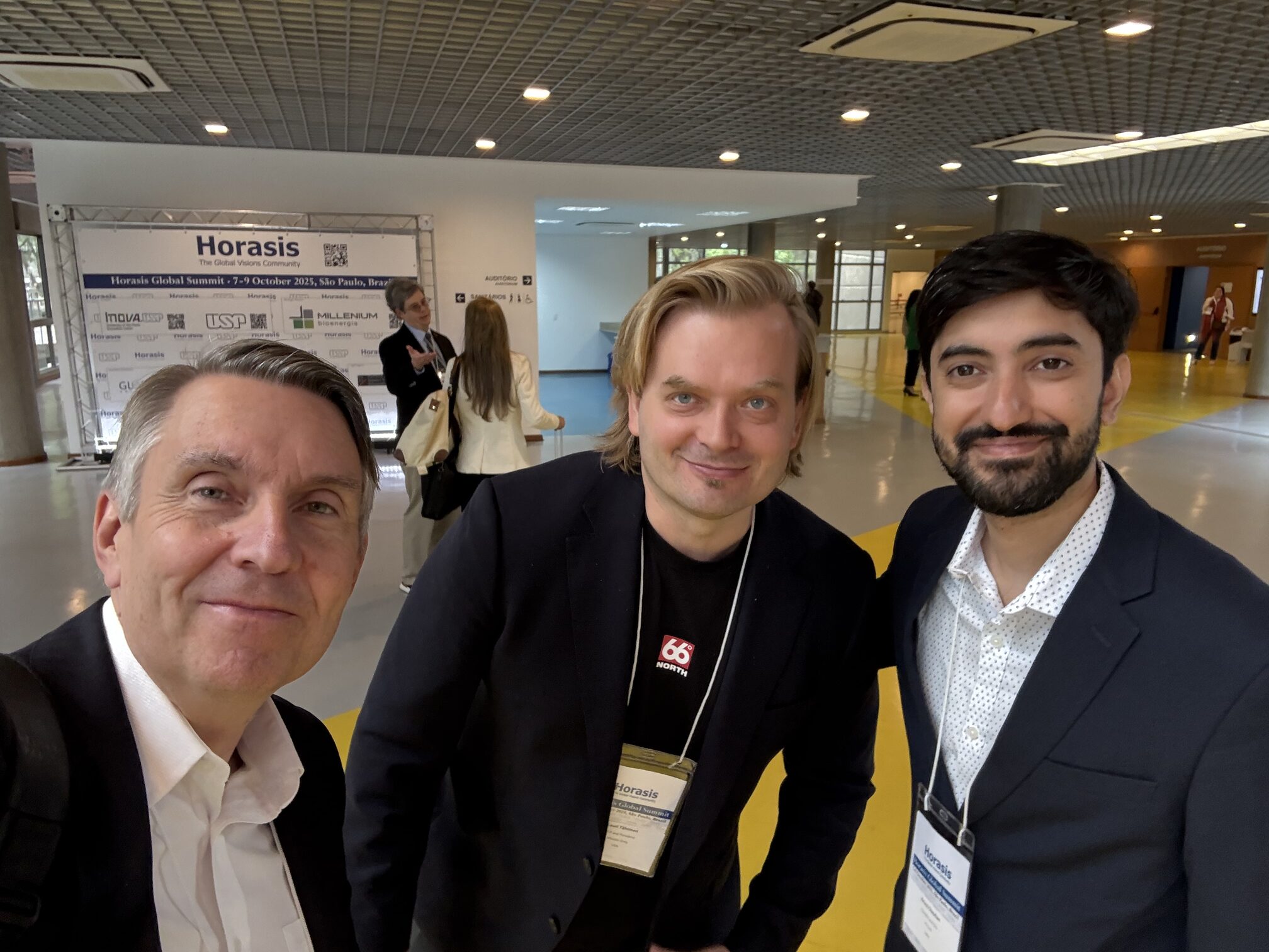 Three attendees photographed at the Horasis venue in São Paulo, with event signage behind them.